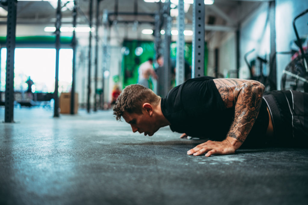 Bryce demonstrates how to do burpees exercise during a workout
